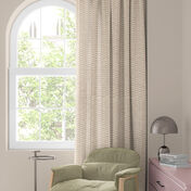 Vindue med farverigt blomsterforh&aelig;ng i r&oslash;dt, orange og bl&aring;t, gr&oslash;n stol og lille bord med lampe